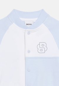 Λευκό και ανοιχτό μπλε βρεφικό μπουφάν με κουμπιά τύπου σναπ, ριμπ γιακά και διπλό λογότυπο "B" στο στήθος.