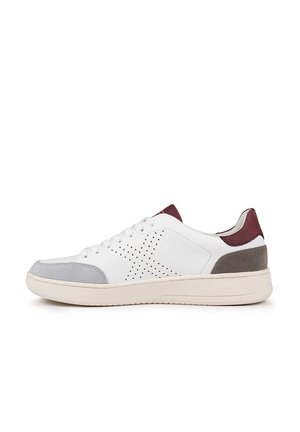 Zapatilla blanca de cuero con acentos en gamuza gris en la puntera y el talón. Presenta un diseño perforado en el lateral y una suela de goma redondeada. Lengüeta del talón en burdeos.