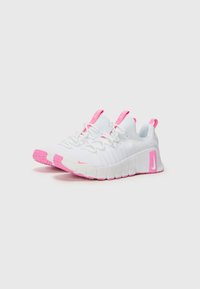 Hvide sportssko med pink detaljer, der har en tekstureret overdel, snørebånd og en tyk gummisål med et rillet mønster.