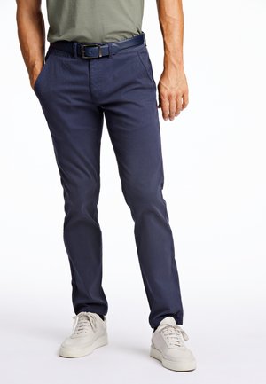 Mörkblå chinos i bomull med en slät yta, med en standard passform, bältesöglor och djupa sidfickor, i kombination med vita sneakers.