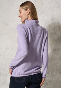 Hellpurpurner Fleece-Pullover mit hohem Kragen, langen Ärmeln und gerafftem Saum. Verfügt über eine weiche Textur und eine figurbetonte Passform.