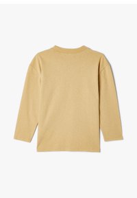 Långärmad skjorta i ljusbeige bomull med rundad halsringning och avslappnad passform. Har platta sömmar och en mjuk yta.