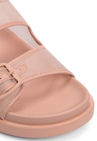 Sandale de couleur pêche avec une semelle lisse et arrondie, des sangles en mesh transparent et une boucle centrale pour l'ajustement.
