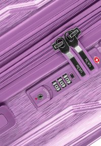 Purple hard-shell suitcase featuring a textured finish, dual metallic zippers, combination lock, and TSA-approved security feature.