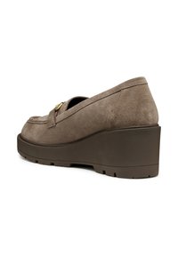 Zapato de cuña de ante topo con un diseño curvado, punta redondeada y suela de goma. Presenta una correa decorativa y un acento en tono dorado.
