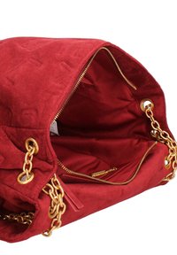 Sac à main en daim rouge avec une bandoulière en chaîne dorée. Comprend une fermeture zippée, une poche intérieure et une texture douce. S'ouvre largement pour un accès facile.