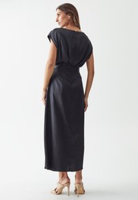 Black dress with short sleeves, belted waist, and a long, flowing design. Smooth texture with a subtle sheen and back zip detail.