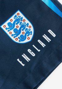 Námořnická tkanina s bílým štítem, na kterém jsou modří lvi a červené růžové akcenty, s nápisem "ENGLAND" tučným bílým písmem pod emblémem.