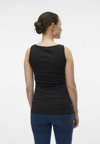 Top negro sin mangas en un diseño ajustado, hecho de un material elástico. Llevado con jeans azules, mostrando una textura suave y detalles en el escote.