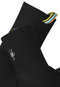 Černé ponožky vyrobené z texturované tkaniny, které mají malý bílý grafický design a barevný pruhovaný akcent na horním okraji.