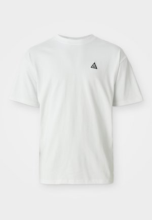 Camiseta branca de manga curta com um pequeno logótipo triangular preto contendo "acg" no lado esquerdo do peito, fundo simples.
