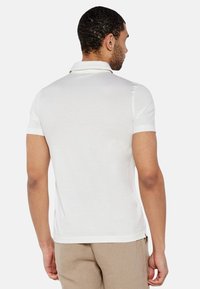Polo shirt bianca a maniche corte con colletto, realizzata in tessuto morbido, caratterizzata da una vestibilità slim e dettagli di cucitura sottile nelle cuciture.