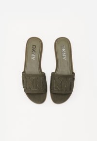 Maslinasto zelene papuče s širokim DKNY logotipom, meka suede tekstura i ravni đonovi. Minimalistički dizajn, pogodne za svakodnevno nošenje.