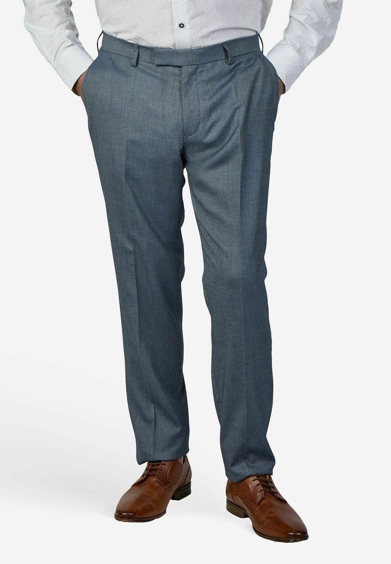 Grijze op maat gemaakte broek met een fijne textuur, platte voorkant en riemlussen, gecombineerd met bruine leren schoenen, tegen een effen witte achtergrond.