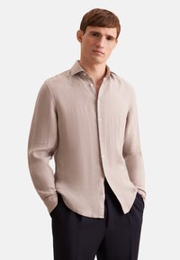 Licht beige overhemd met lange mouwen, een zachte textuur, knoopsluiting aan de voorkant en een klassieke kraag, gecombineerd met donkere broeken.