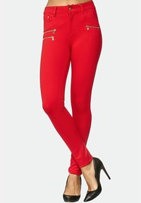 Röda stretchiga skinny jeans med flera dragkedjefickor, en figurnära design och en slät textur. Matchas med svarta högklackade skor.