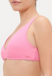 Rózsaszín bordázott bikinifelsőrész V-kivágással, állítható pántokkal és Roxy logóval az oldalon. Sima textúrájú, fitted sziluettel.