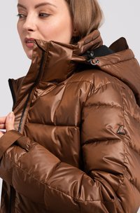 Veste matelassée marron avec une finition brillante. Présente un col haut, une capuche ajustable et une fermeture frontale à glissière. Accentuée par un détail de logo.