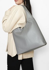 Borsa tote in pelle grigia con finitura testurizzata. Caratterizzata da un corpo grande e spazioso e da una singola tracolla.