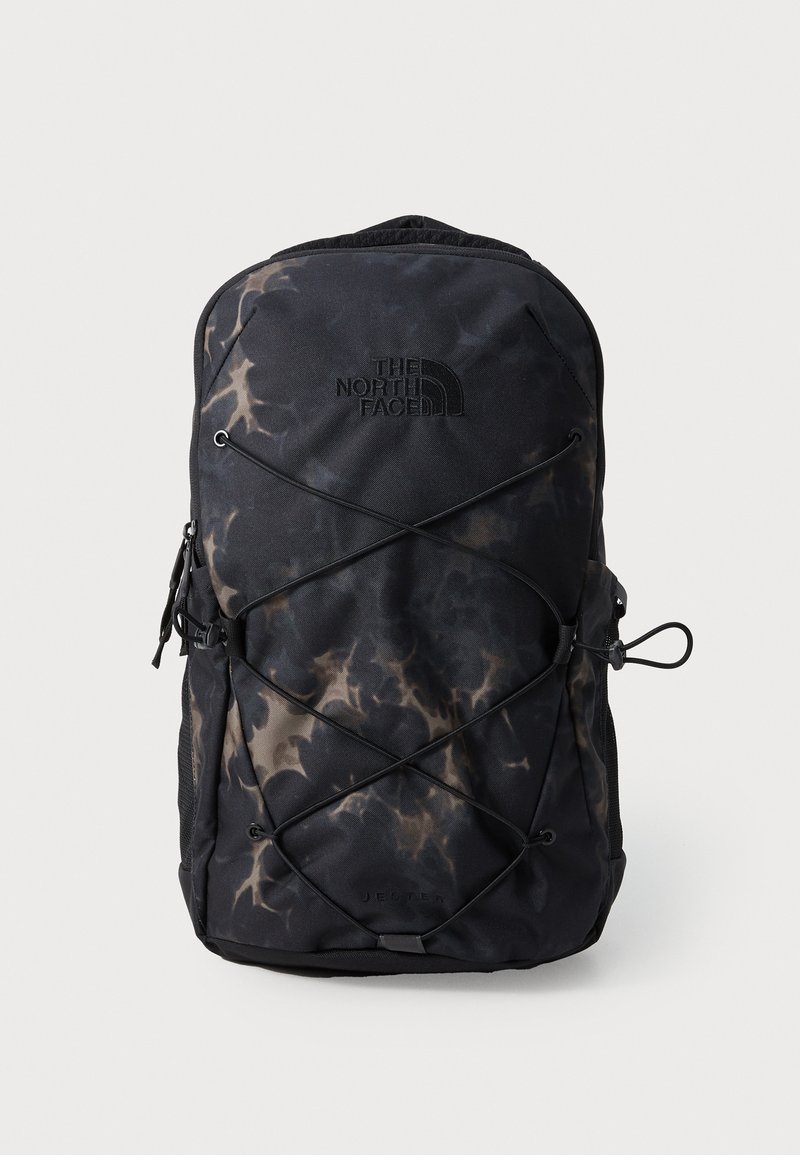 Black backpack with a tie-dye pattern, featuring a prominent logo, bungee cord design, zippered pocket, and padded back.