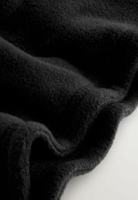 Sort fleece-stof hænger blødt og har en glat tekstur med subtile dybder, samt små variationer i nuancerne og ingen markante mønstre.