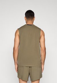 Αμάνικη μπλούζα σε ελιά πράσινο χρώμα, κατασκευασμένη από απαλό ύφασμα, με στρογγυλή λαιμόκοψη και ραμμένα τελειώματα, συνδυασμένη με σορτς στο ίδιο χρώμα.