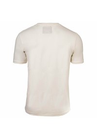 Camiseta de algodón color beige claro con mangas cortas, cuello redondo y una pequeña etiqueta rectangular en la parte superior de la espalda. Textura suave, ajuste regular.