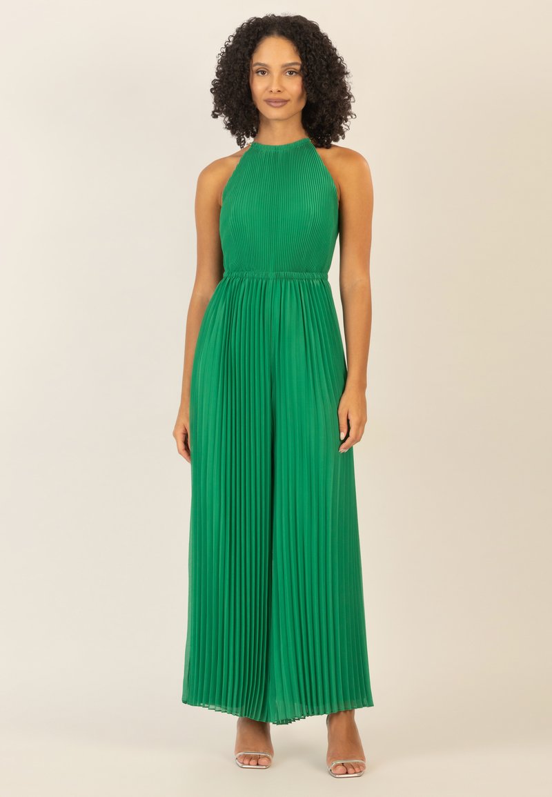 Jumpsuit verde a pieghe con scollatura a halter. Presenta un corpino aderente e pantaloni a gamba larga. Il materiale ha una texture liscia e una leggera lucentezza.