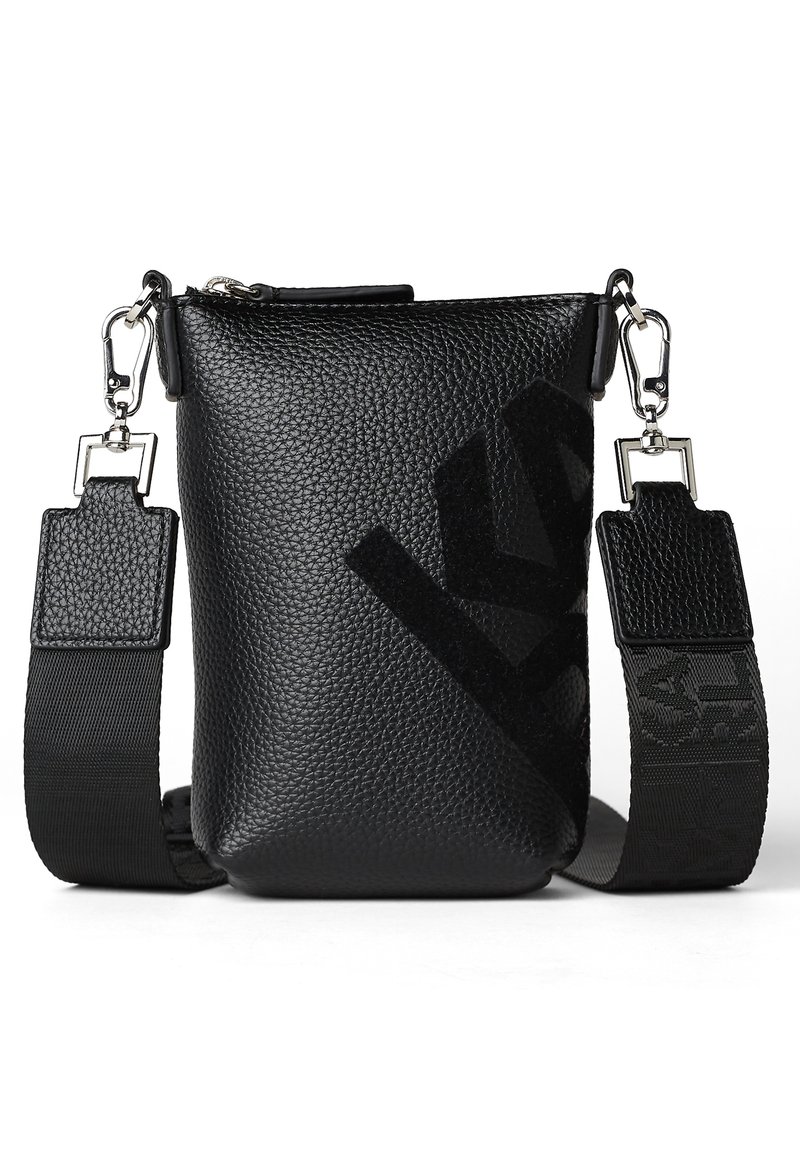 Černá krosna z texturované kůže s nastavitelným popruhem, zdobená výrazným logem a kovovými detaily. Horní zapínání na zip.