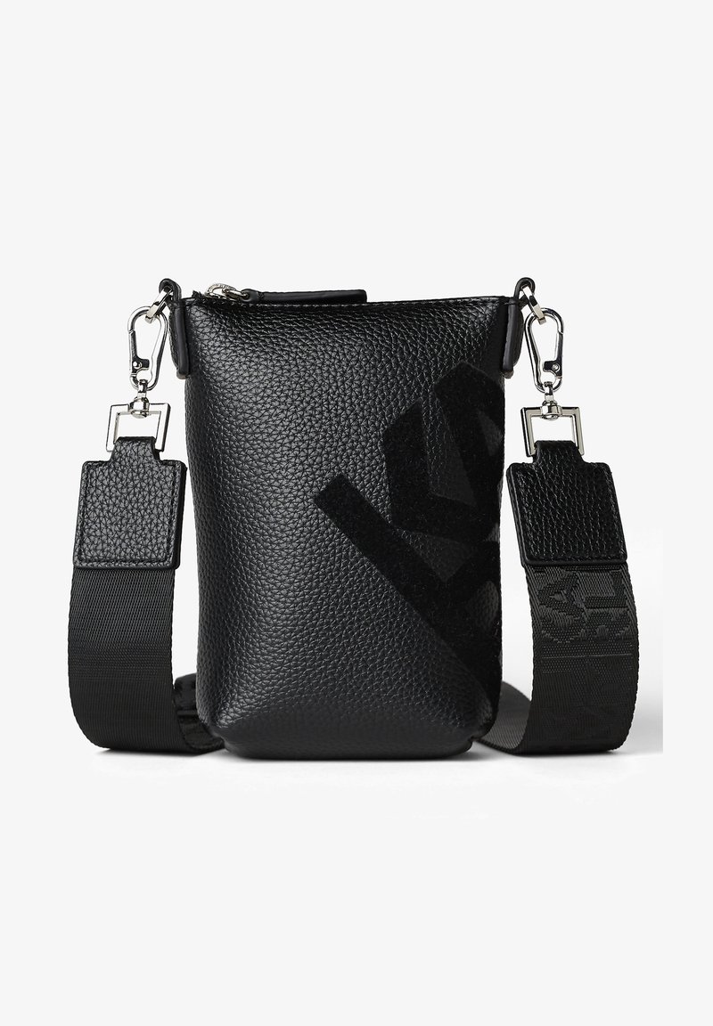 Černá krosna z texturované kůže s nastavitelným popruhem, zdobená výrazným logem a kovovými detaily. Horní zapínání na zip.