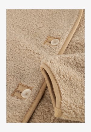 Beige fleece stof met een zachte, gestructureerde afwerking, voorzien van een tan rand en knopenaccenten nabij de gestikte zakken.