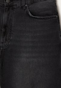 Jeans in denim nero con un design aderente, dotati di una tasca frontale e dettagli di cucitura sottili. La texture è liscia con una leggera lucentezza.