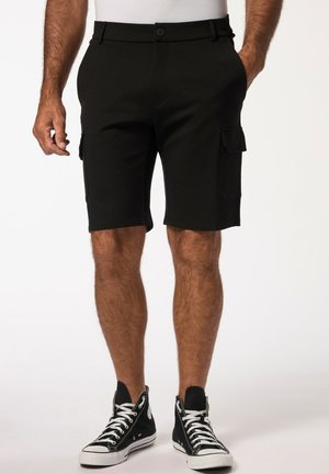 Schwarze Cargo-Shorts aus elastischem Stoff, mit Seitentaschen, Knopfverschluss und geradem Schnitt. Kombiniert mit schwarzen, hochgeschnittenen Sneakers.