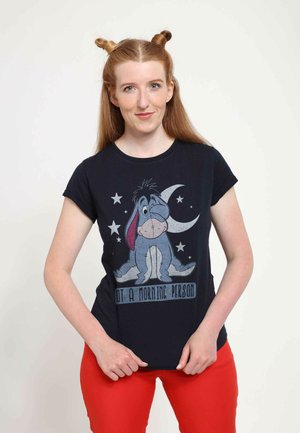T-shirt bleu marine avec un graphique d'Eeyore, des étoiles et un croissant de lune. Le texte en dessous indique "Pas une personne du matin." Manches courtes, col rond.