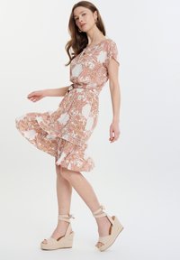 Vestido midi con estampado floral en tejido ligero, con mangas cortas, cintura ceñida y dobladillo con volantes, combinado con cuñas de esparto beige.