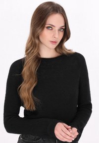 Pulover negru tricotat cu un finisaj texturat, guler rotund și mâneci lungi. Croiala este lejeră, iar materialul pare confortabil.