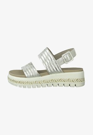 Sandal metálico plateado con dos bandas anchas y estriadas, hebilla ajustable en el tobillo y una suela blanca gruesa y texturizada con diseño trenzado.