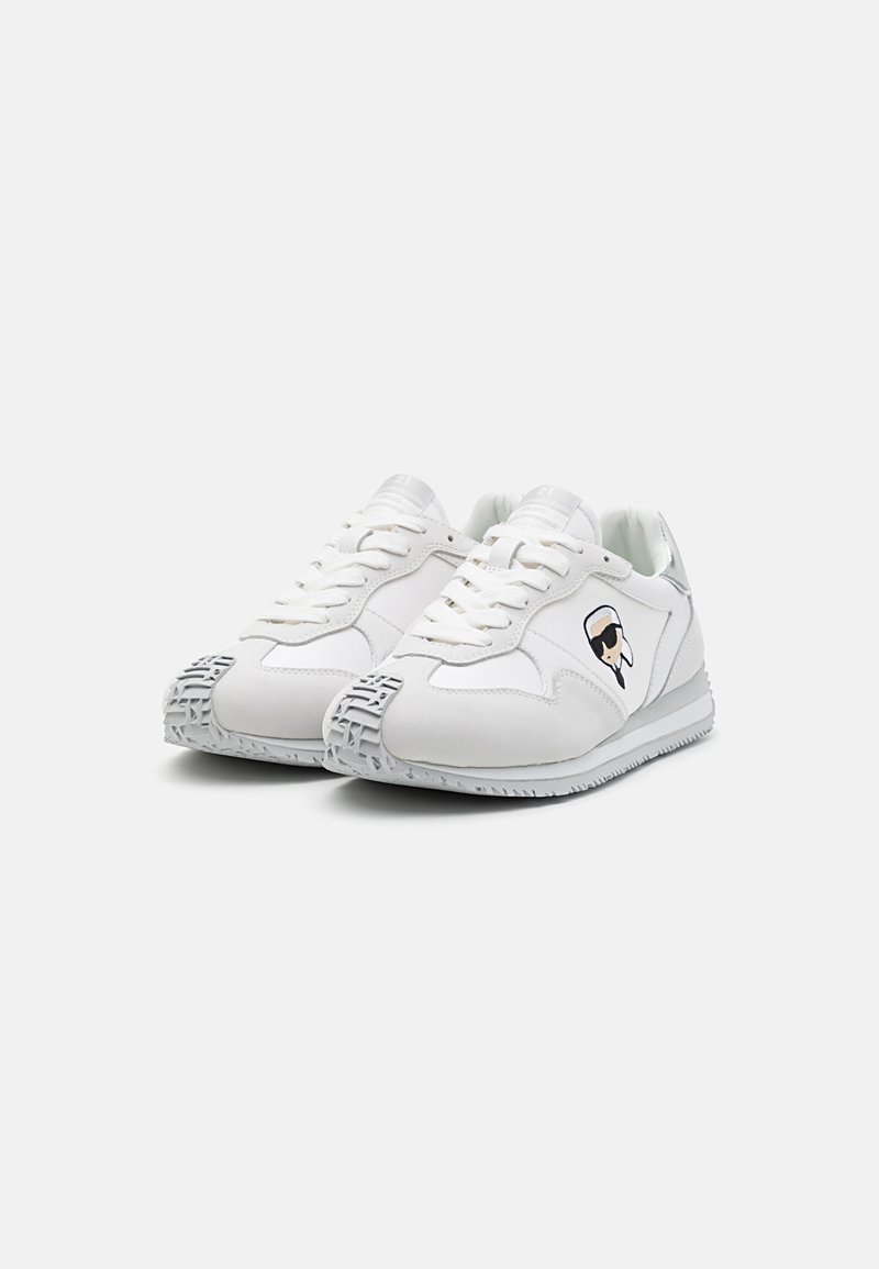 Zapatillas blancas con parte superior de cuero suave, diseño de cordones, suela de goma texturizada y un pequeño logotipo en el lateral.
