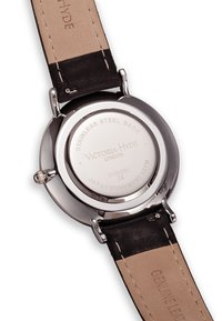 La parte trasera del reloj de acero inoxidable tiene grabado el nombre de la marca, movimiento japonés, con una correa de cuero genuino negro y parte inferior de color marrón claro.