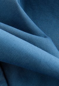 Textureret blå stof med et vævet mønster, der har en glat overflade med forskellige nuancer af blå, hvilket skaber dybde og dimension.