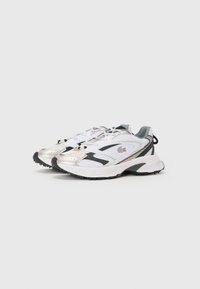 White and silver athletic sneakers with a mesh upper, black accents, textured sole, and contrasting heel tab, designed for performance.