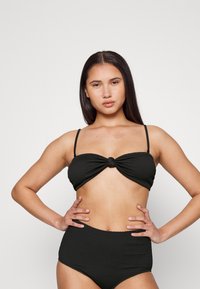 Conjunto de biquíni preto com um top bandeau texturizado com detalhe em nó e alças ajustáveis, combinado com um fundo de cintura alta.