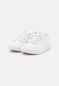 Baskets de tennis blanches avec une tige en cuir lisse, bout rond, devant à lacets, semelle en caoutchouc texturée et un discret logo au niveau du talon.