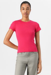 Haut ajusté à manches courtes en tissu côtelé rose vif avec un col rond. Associé à un pantalon droit gris. Design simple, sans motifs.