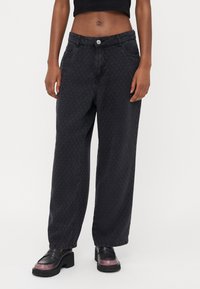 Zwarte denim wijde broek met een gestructureerd geruit patroon, voorzien van zijzakken en een knoopsluiting bij de taille.
