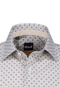 Camicia bianca con tessuto a fantasia caratterizzato da forme geometriche in blu, marrone e giallo. Colletto standard e chiusura con un solo bottone.