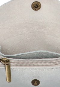 Bolso de cuero blanco con textura suave, un compartimento con cremallera y cierre de broche metálico. El forro interior es liso y de color claro.
