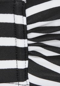 Tessuto a righe bianche e nere caratterizzato da una texture arricciata, con righe di diversa ampiezza alternate e dettagli di cucitura puliti.