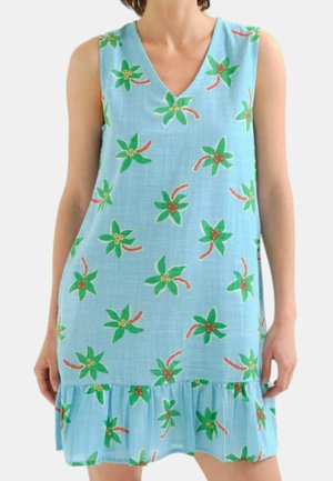 Robe bleu clair sans manches avec un motif floral vert et rouge et un ourlet volanté portée par une personne debout.