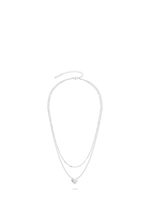 Doppellagige Silberkette mit kleinem, geometrisch geformtem, herzförmigem Anhänger und verstellbarem Verschluss.